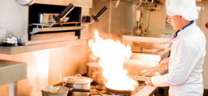 Chef standing at a stove and cooking a flaming dish